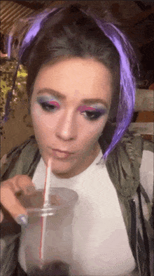 a woman with purple hair is drinking through a plastic straw