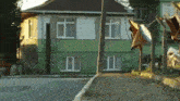 a green and white house with clothes hanging on a line in front of it