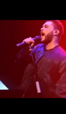 a man with a beard is singing into a microphone on stage .