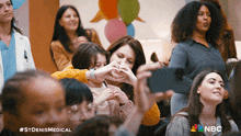 a woman is taking a picture of a little girl making a heart shape with her fingers