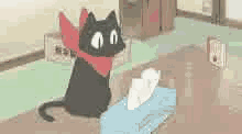 a black cat wearing a red scarf is sitting on top of a tissue box .