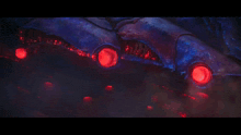 a close up of a blue object with red lights coming out of it 's mouth
