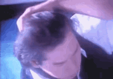 a man in a suit and tie is scratching his head