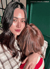 a woman is hugging another woman in front of a door