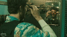 a man adjusts his sunglasses in front of a mirror with the word prime on the bottom right