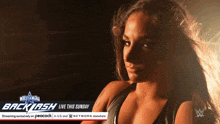 a woman stands in front of a sign that says wrestlemania backlash