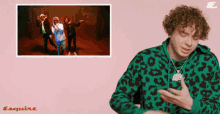 a man in a green leopard print sweatshirt is standing in front of a pink background with esquire written on it