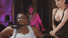 a woman in a white tank top is standing in front of a mirror and making a funny face .