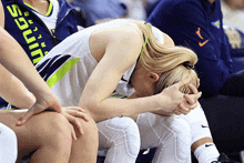 a female basketball player sits on the bench with her head on her knees