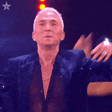 a man wearing a blue jacket and a black shirt with a star on the bottom
