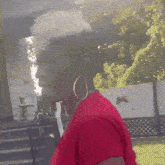 a woman wearing hoop earrings and a red shirt stands in a park