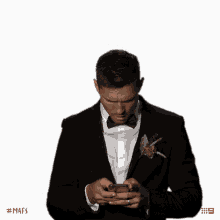 a man in a tuxedo is looking at his phone with the hashtag #mafs
