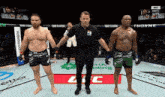 two men are standing next to each other in a boxing ring while a referee stands between them .