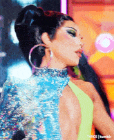 a close up of a woman wearing hoop earrings and a sequined top