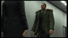 a man in a green parka is standing next to another man in a black suit
