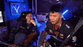 two men are shaking hands in front of a microphone while sitting in chairs in a room .