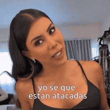a woman in a black tank top with yo se que estan atacadas written above her