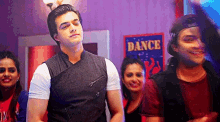 a group of people are standing in front of a dance sign