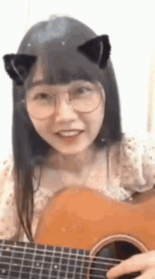 a girl with cat ears is playing a guitar