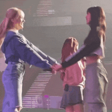 a group of women are dancing on a stage and one of them is holding another woman 's hand .