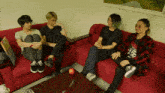 a group of young men sit on a red couch in a room