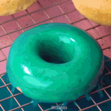 a blue donut is sitting on a cooling rack with the words mr.cakes written below it