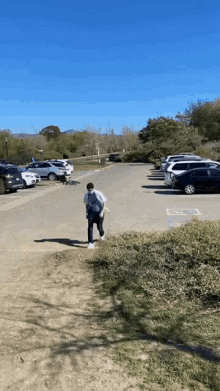 a man wearing a mask is walking across a parking lot