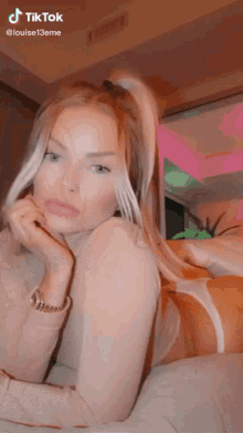 a woman is laying on a bed with her hand on her face and a tiktok watermark on the bottom