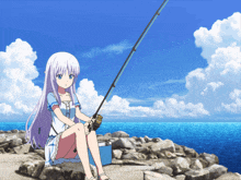 a girl sitting on a rock with a fishing rod