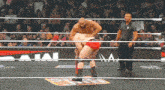 a wrestler in a red shorts is being lifted by another wrestler in a wrestling ring