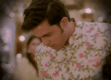 a man wearing a floral shirt looks down at something