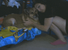 a woman is kneeling down next to a dog on a bed with a lego box in the background