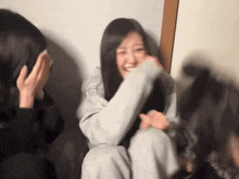 a girl with long hair is laughing while another girl covers her face