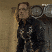 a man with long hair is wearing a black shirt that says max on it