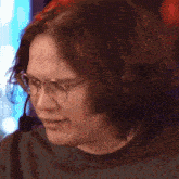 a man wearing glasses and a microphone looks down