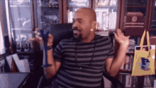 a man in a striped shirt is sitting in a chair holding a glass .