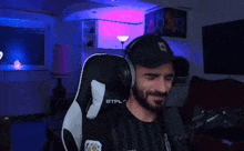 a person wearing headphones is sitting in a gaming chair in a room .