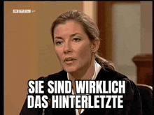 a woman in a judge 's robe is sitting in front of a screen that says sie sind wirklich das hinterletzte