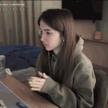 a girl with green nails is sitting at a desk with a laptop