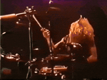a woman playing drums in front of a microphone in a dark room