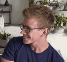 a young man wearing glasses and a blue shirt smiles