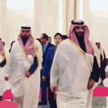 a group of men in traditional arabic clothing are walking in a room