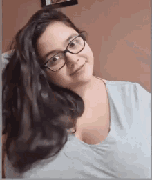 a woman wearing glasses and a blue shirt is looking at the camera and smiling .