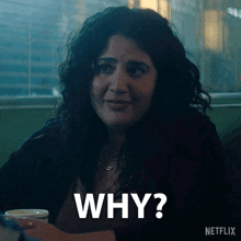 a woman is sitting at a table with a cup of coffee and a sign that says " why "