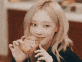 a woman with blonde hair is holding a chocolate chip cookie in her hand