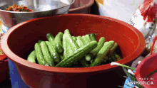 a large red bowl filled with green cucumbers is made in animatica