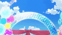 a colorful archway with balloons and a red ribbon in front of a blue sky