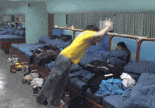 a man in a yellow shirt is standing in front of a bed with a pillow that says glow