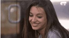 a woman with long hair is smiling and looking at the camera in a blurry photo .