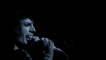 a close up of a person singing into a microphone in the dark .